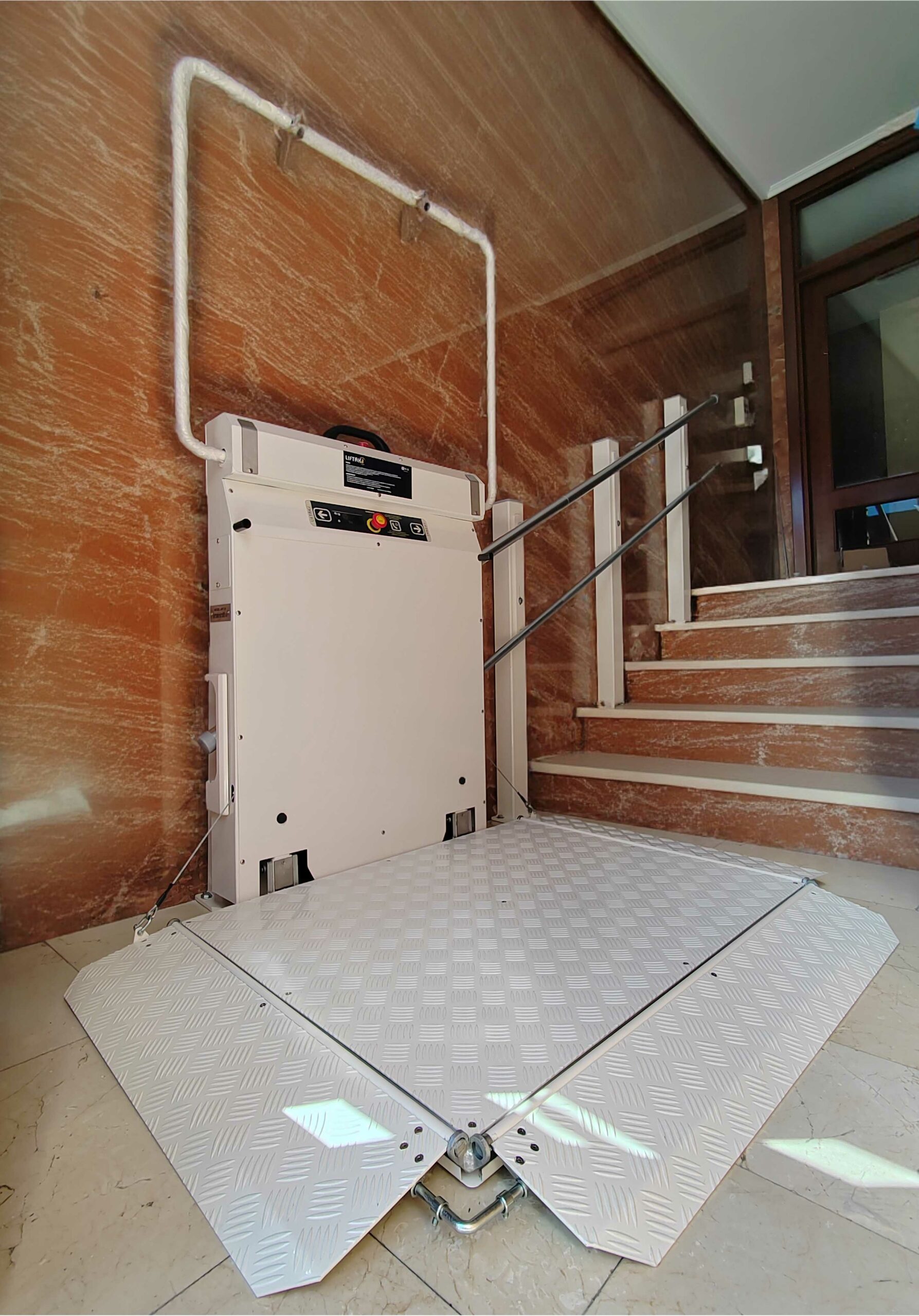 Instalación de elevador salvaescaleras en comunidad de vecinos – Subir Fácil Presidenta de comunidad en el portal del edificio tras la instalación de un elevador salvaescaleras